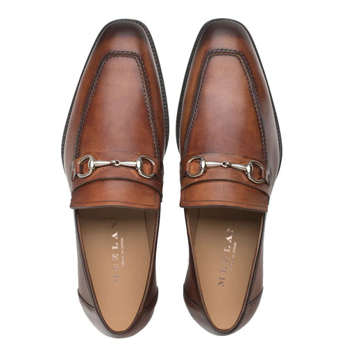 Mezlan cognac loafers: Elongated shape, rounded toe, smooth leather. Metal chain accent. Rich cognac color, contrasting stitching. Slip-on style. Light interior lining. Sturdy outsole.
