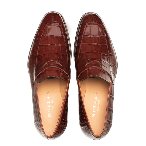 Mezlan Piccolo penny loafer in glossy burgundy alligator. Elongated shape, textured like crocodile skin, rounded toe, low profile, and beige interior lining.
