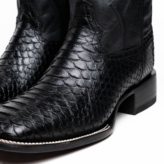 Black python cowboy boots by Marco Di Milano. Square toe, textured scale pattern. Smooth leather upper, low stacked heel, decorative stitching. Sleek design.

