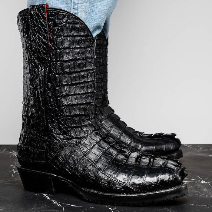Marco Di Milano Marlboro Black cowboy boots. Black hornback crocodile tail leather upper with textured scales & pointed toe. Tall shaft, curved top, reinforced stitching. Rugged tractor sole. High-quality, traditional design.
