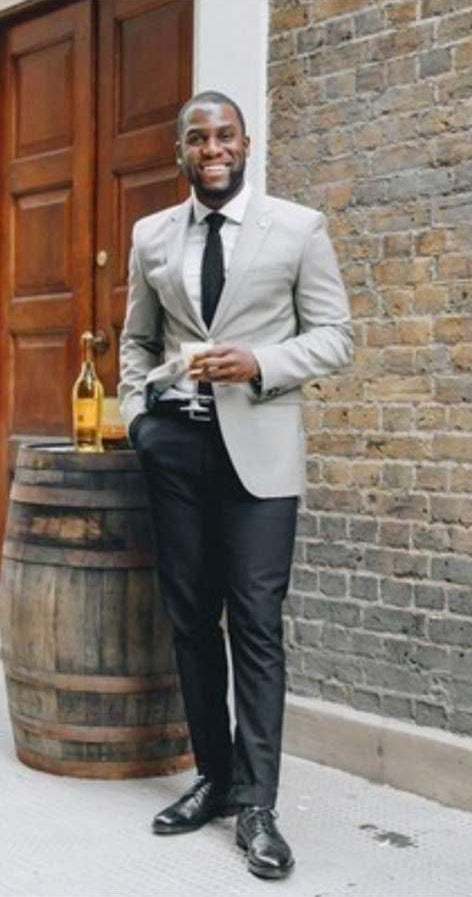 Light grey slim-fit blazer with a single button closure, paired with black tailored pants. Structured shape, smooth fabric, and two front pockets on the blazer. Cohesive, formal look.
