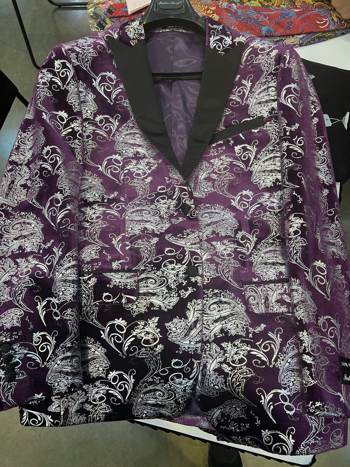 Men's tuxedo jacket with purple/white paisley floral brocade. Black satin lapel, two pockets, and a glossy finish. Intricate designs throughout.
