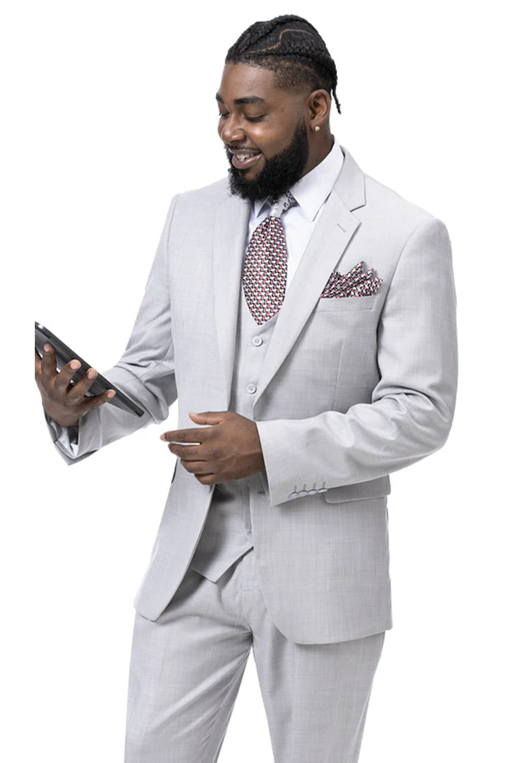 Light gray men's three-piece wedding suit. Features a structured, two-button jacket, matching waistcoat and trousers. Smooth fabric with subtle texture. Patterned tie and pocket square provide contrast.
