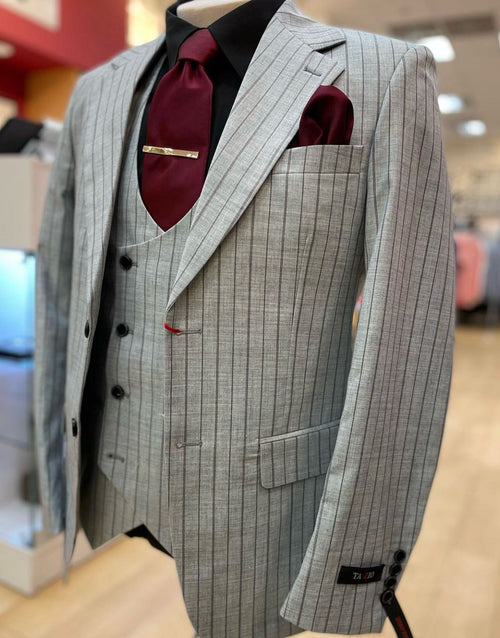 Men's light grey pinstripe three-piece suit with a vest. Textured fabric, narrow stripes, single-breasted jacket, and matching vest. Burgundy tie & pocket square. Tailored fit, slightly padded shoulders.
