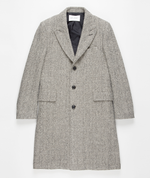 Men's grey herringbone long overcoat. Structured silhouette, notched lapel, button closure, and long sleeves. Features a grey herringbone pattern, two front pockets, and a black interior lining.
