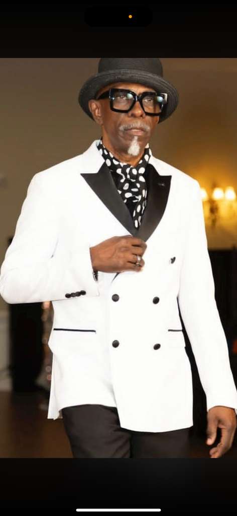 Men's white double-breasted slim-fit tuxedo with black satin lapels and front pockets. Includes black trousers for a formal, modern appearance.
