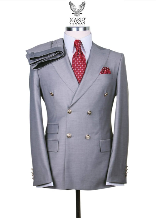 Light grey double-breasted suit with wide lapels and button rows. Includes front and chest pockets. Paired with a red patterned tie and pocket square. Trousers are folded, highlighting structured tailoring.
