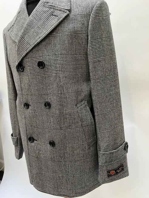 Men's grey plaid double-breasted overcoat with black faux fur collar. Structured silhouette, two rows of buttons, check pattern in grey shades. Tailored sleeves, buttoned cuffs, integrated side pockets.
