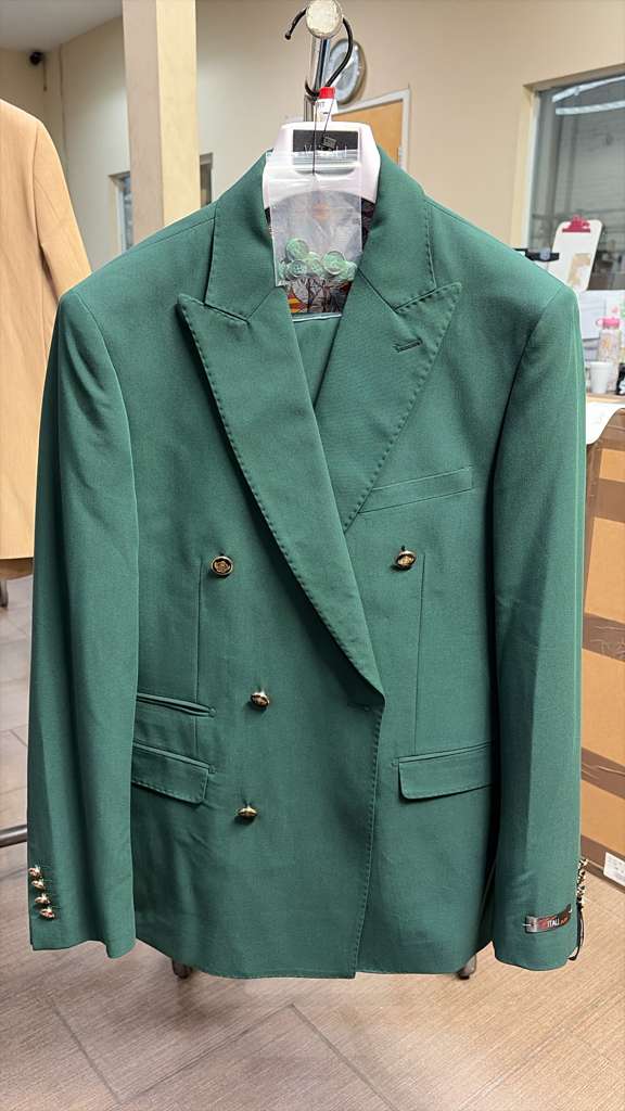 The vitali brand men’s emerald green double-breasted suit features a structured design with two rows of buttons and a notched lapel. The fabric appears smooth, with two side pockets and button details on the sleeves.