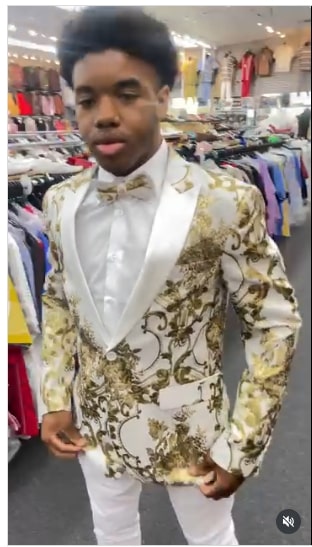 Men's formal tuxedo jacket: white base, gold floral pattern. Features satin lapel and bow tie. Structured blazer design with intricate swirling and floral motifs.
