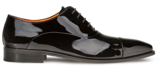 Glossy black patent leather Oxford with pointed toe, five-eyelet lacing, and a thin heel. Interior is lined with vibrant orange material. Reflective, sleek design.
