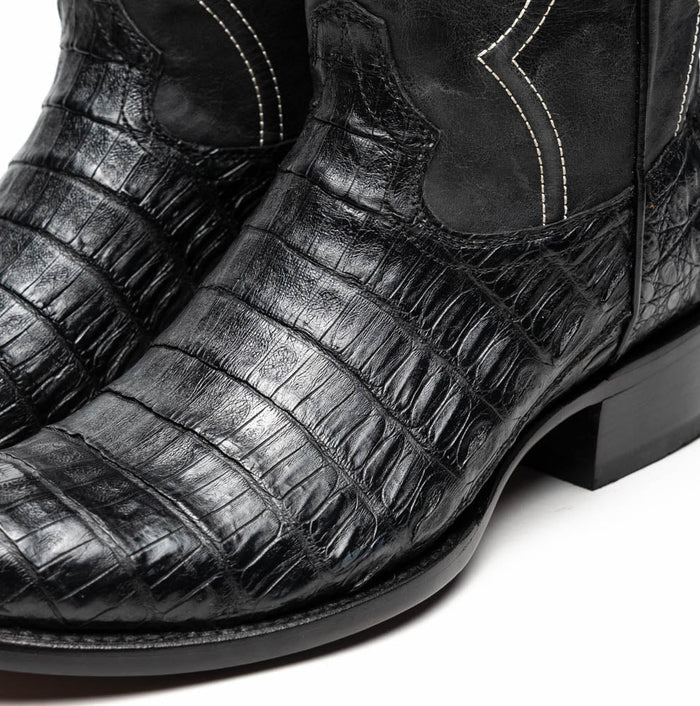Marco Di Milano Phoenix cowboy boots in black caiman crocodile leather. Round toe, textured upper with scales and glossy finish. White stitching accents the seams. Black leather shaft, sturdy black sole.
