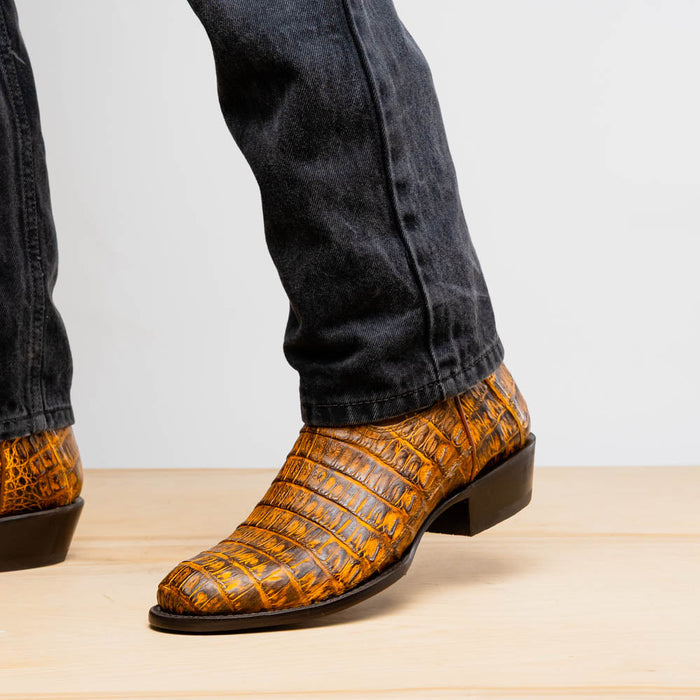 Mustard brown Marco Di Milano Phoenix cowboy boots. Caiman crocodile leather with a textured pattern, round toe, low heel, and black sole.
