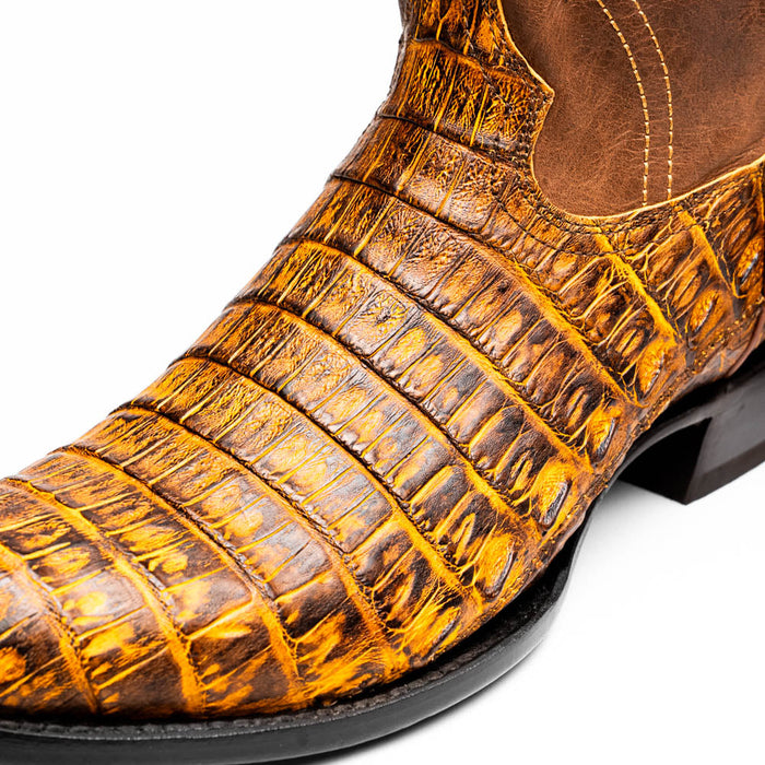 Marco Di Milano Phoenix cowboy boots in mustard brown caiman crocodile leather. Round toe, textured scales. Brown interior, black sole. Distinct design with depth.
