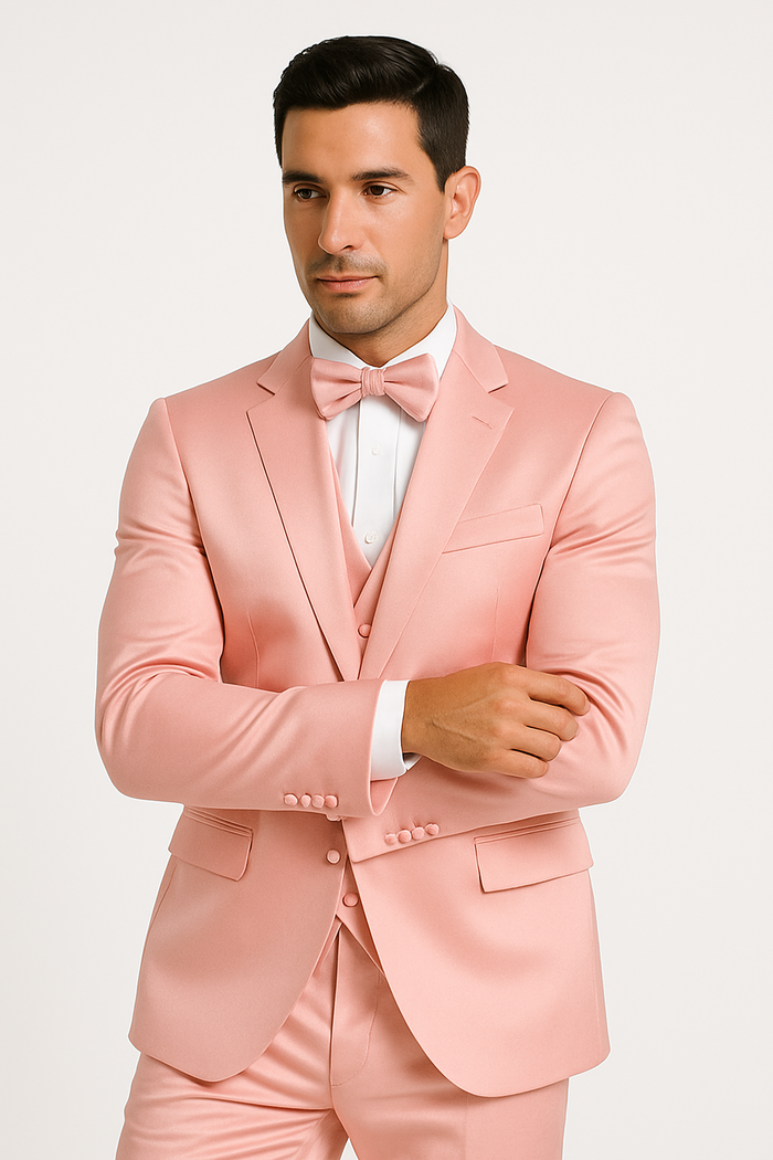 Light pink tuxedo set: fitted satin blazer, matching trousers, white dress shirt, and bow tie. Features notched lapel, side pockets, and a visible waistcoat. Shirt with contrasting white cuffs.
