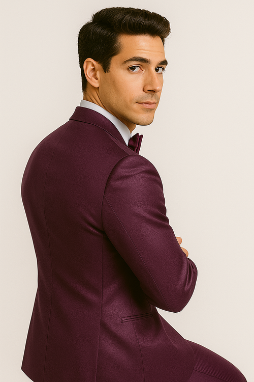 Alberto Nardoni's purple tuxedo set: fitted jacket with smooth, shiny fabric, peak lapels, and discrete pockets. Features a rich purple color with a contrasting black bow tie. Matching purple trousers.
