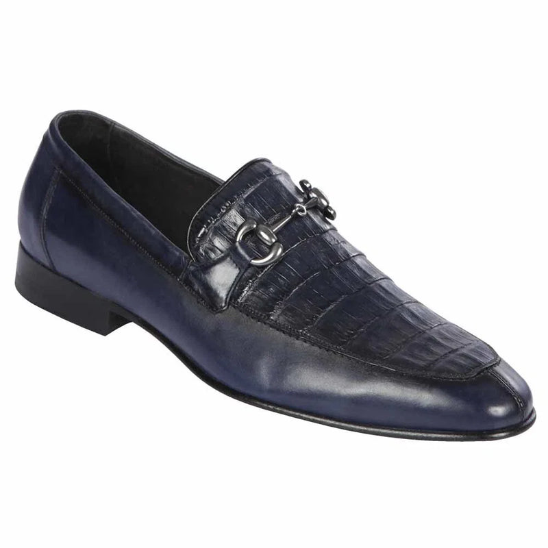 Navy men's slip-on dress shoe. Genuine crocodile skin front, calfskin panel. Rounded toe, low square heel, glossy finish. Decorative metal detail on strap. Tapered shape.
