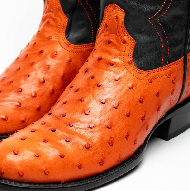 Marco Di Milano orange ostrich cowboy boots. Round toe, bright orange upper with raised bumps, black sides. Orange stitching details. Flat black sole.
