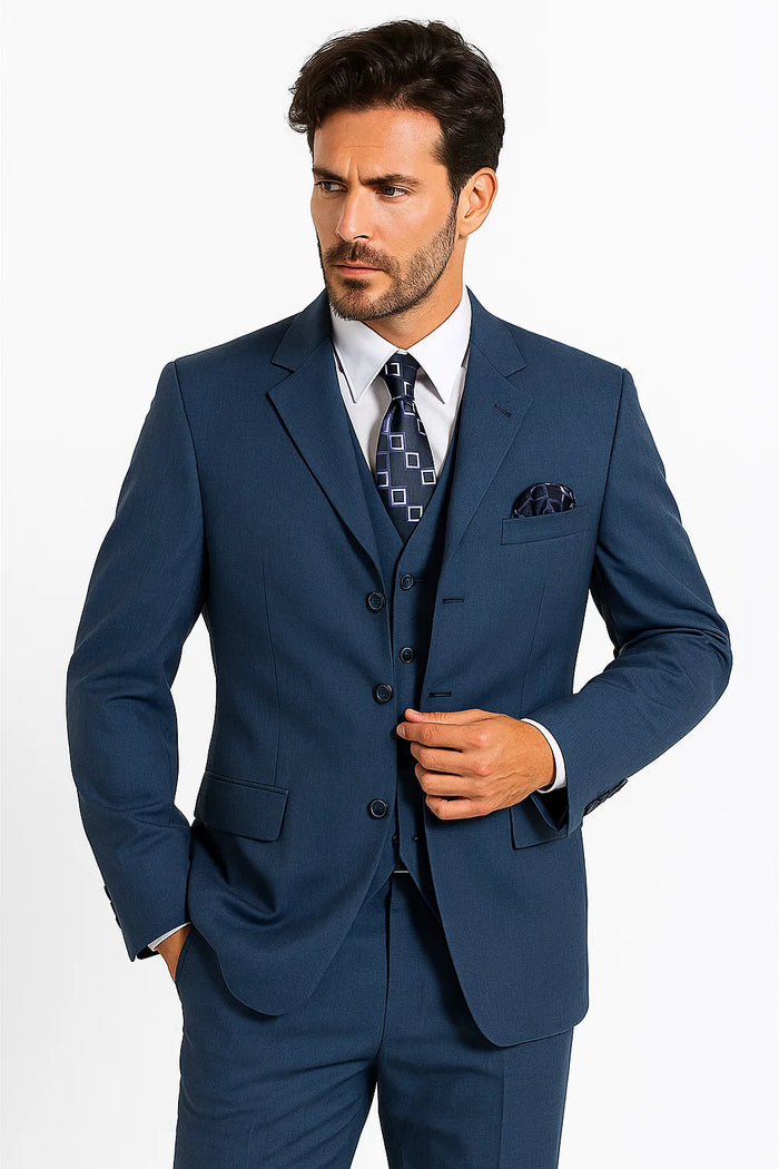 Sapphire blue men's suit jacket. Structured, peak lapel, straight cut. Smooth fabric, three buttons, flap & breast pockets, pocket square. Tapered sleeves with buttoned cuffs. White shirt, patterned tie.
