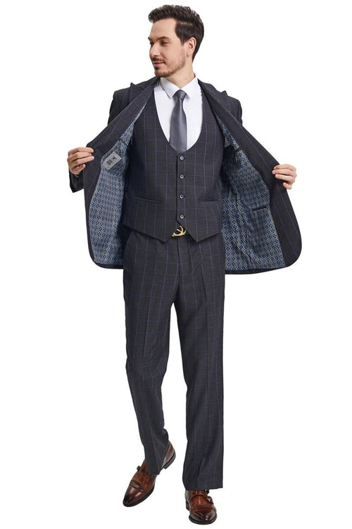 Men's charcoal grey suit featuring a peak lapel and windowpane plaid pattern. The ensemble includes a scoop neck vest and is complemented by a patterned lining visible inside the jacket.