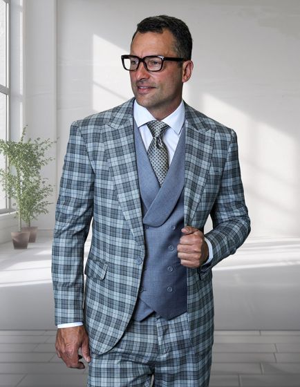 The Statement mens 3 piece plaid suit features a modern fit design constructed from 100% wool. The suit includes a blazer with a predominantly light gray and dark blue plaid pattern, a matching vest in a lighter blue shade, and tailored trousers.