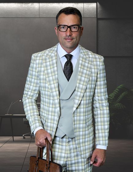 The Statement mens 3 piece plaid suit is composed of 100% wool, featuring a fitted blazer, matching vest, and trousers. The suit displays a light plaid pattern in shades of green, white, and gray. The components are tailored with modern lines and a structured fit.