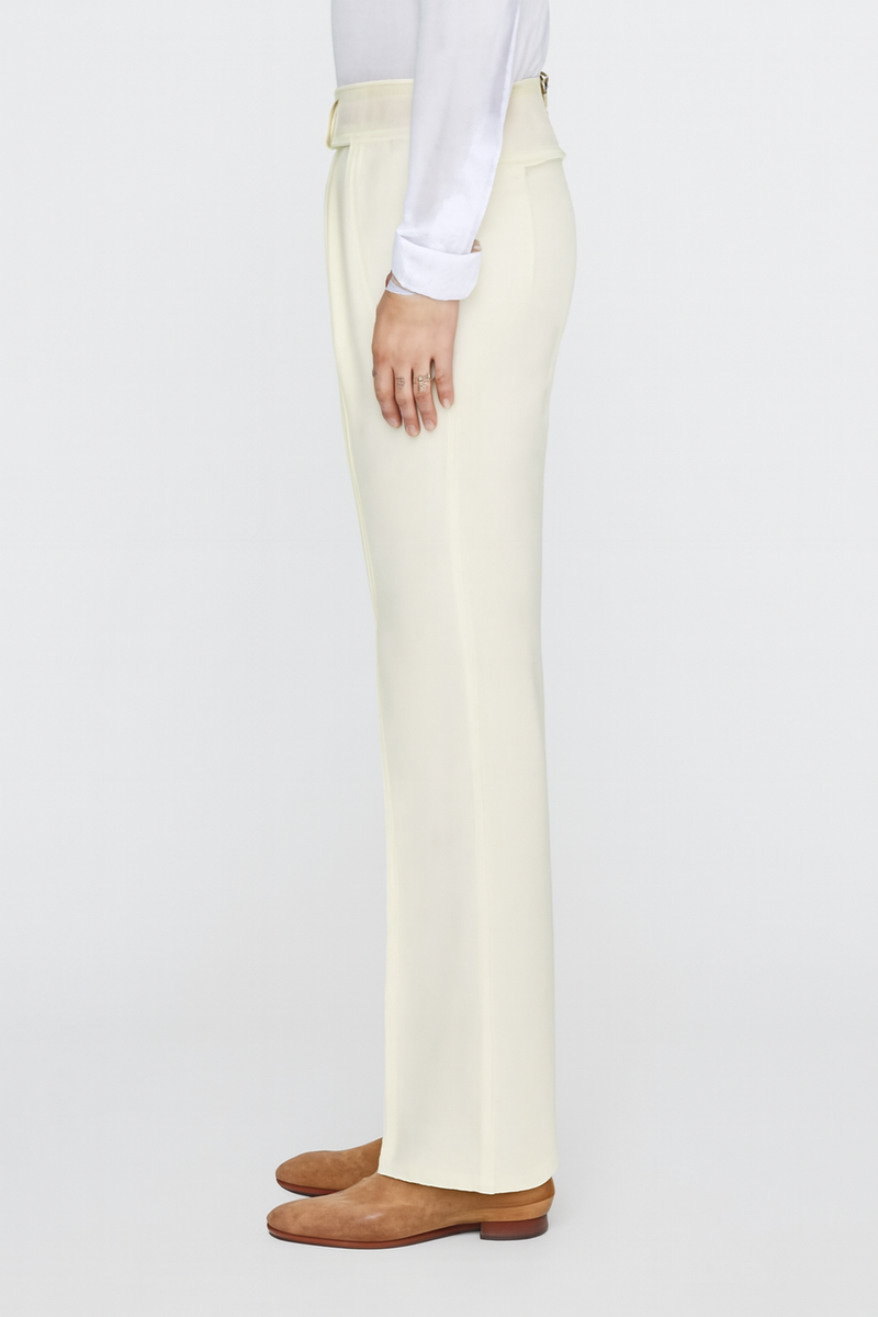 Tiglio Luxe off-white Marbella dress pants. Semi-wide leg, tailored silhouette with a slight flare. Lightweight wool blend fabric. Features a clean, minimalist design with a waistband, belt loop, button closure, side pockets, and a center crease.
