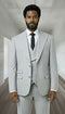 The Statement mens 3 piece modern fit suit features peak lapels, a double-breasted vest, and flat-front trousers. It is constructed from 100% wool and presented in a light grey color. The tailored fit emphasizes a structured silhouette with two front pockets on the jacket.
