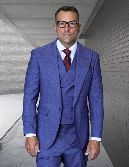 The Statement mens 3 piece suit is crafted from 100% wool, featuring a modern fit. It is primarily a textured blue color with a windowpane pattern. The suit includes a two-button blazer, a matching vest, and trousers, all with a structured silhouette.