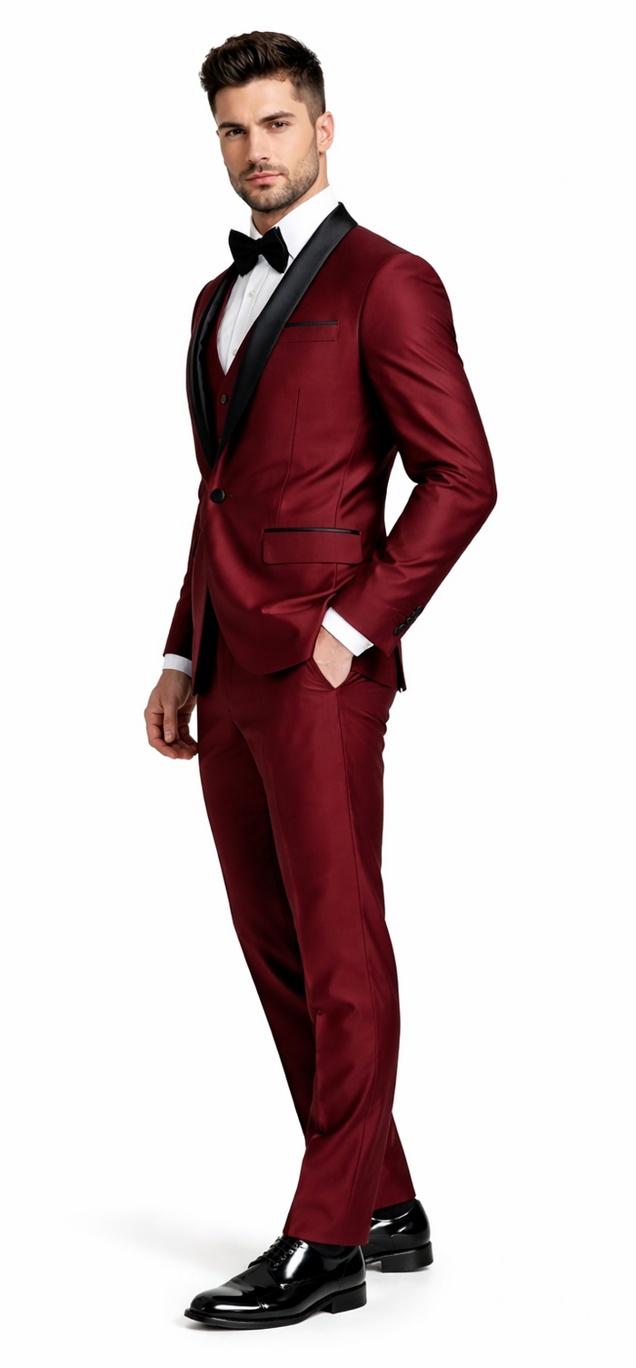 Burgundy three-piece tuxedo with shawl lapel, vest & tailored trousers. Smooth, shiny fabric. Black accents on lapel and pockets, creating an elegant look.
